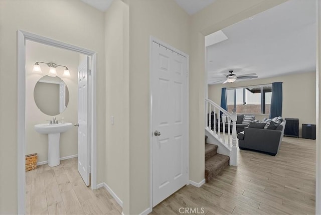10969 Elkwood Cir, Riverside, CA 92503 - corridor with light wood-type flooring, stairway, baseboards, and a sink