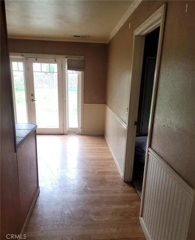 hall with visible vents, a healthy amount of sunlight, ornamental molding, and wainscoting