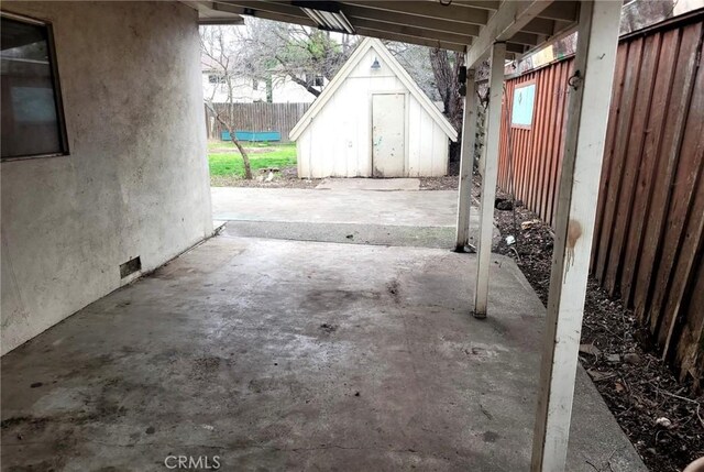 view of patio / terrace with fence, a storage unit, and an outbuilding