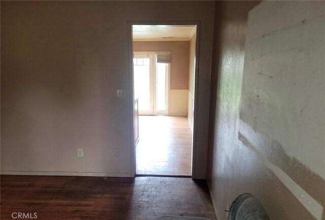 hallway featuring wood finished floors, a wainscoted wall, and ornamental molding