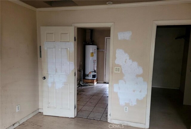 empty room with baseboards, gas water heater, and crown molding