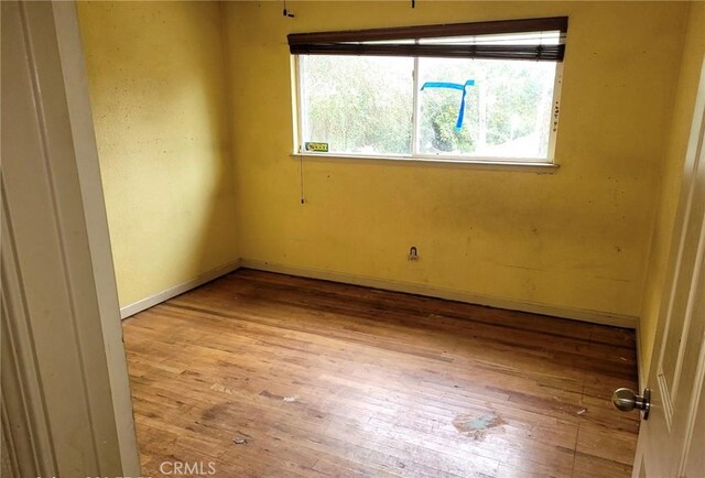 spare room with hardwood / wood-style floors and baseboards