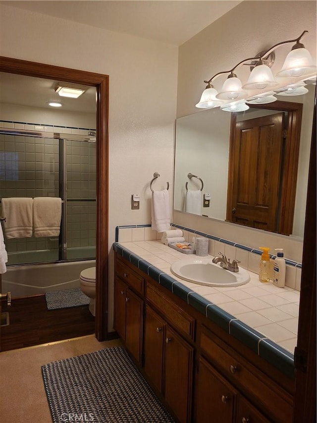 full bathroom featuring toilet, vanity, and combined bath / shower with glass door
