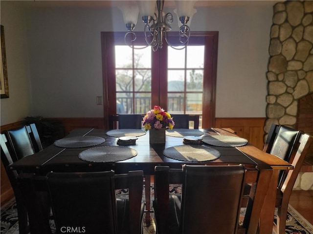 dining area featuring a wainscoted wall and a notable chandelier