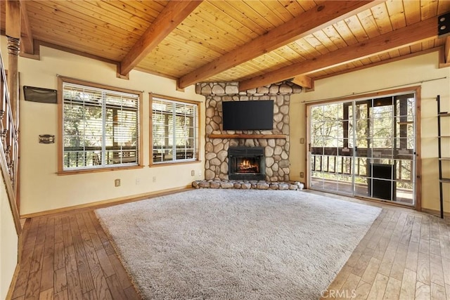 14521 Voltaire Dr, Pine Mountain Club, CA 93222 - unfurnished living room featuring hardwood / wood-style flooring, a stone fireplace, baseboards, plenty of natural light, and wooden ceiling with exposed beams