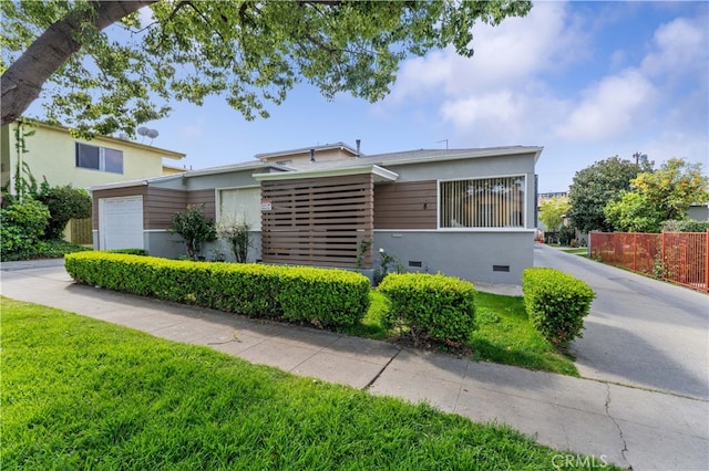 view of front of house with fence, a garage, and stucco siding