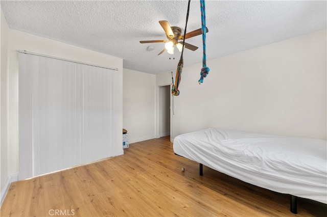 bedroom with a textured ceiling, wood finished floors, and a ceiling fan