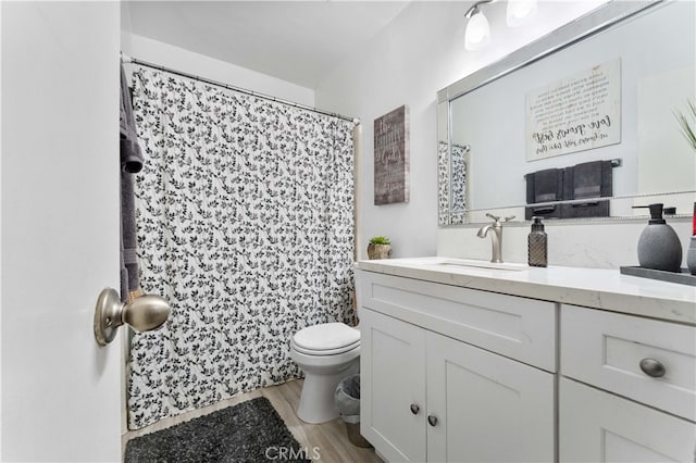full bath with toilet, vanity, and wood finished floors