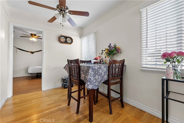 dining space featuring light wood-style flooring, ceiling fan, plenty of natural light, and baseboards