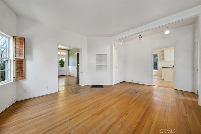 1811 Chorro St, San Luis Obispo, CA 93401 - unfurnished living room with light wood finished floors, rail lighting, and a notable chandelier