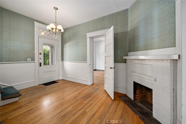 1811 Chorro St, San Luis Obispo, CA 93401 - entrance foyer with an inviting chandelier, a fireplace, wood finished floors, wallpapered walls, and a wainscoted wall