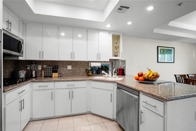 5224 Zelzah Ave Unit 108, Encino, CA 91316 - kitchen featuring a peninsula, a sink, a tray ceiling, stainless steel appliances, and backsplash