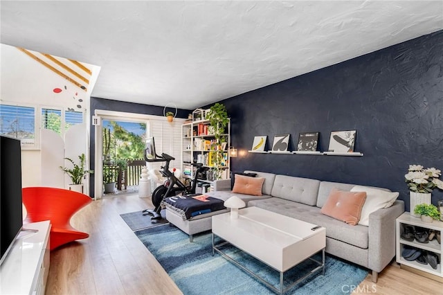 living area with an accent wall and wood finished floors