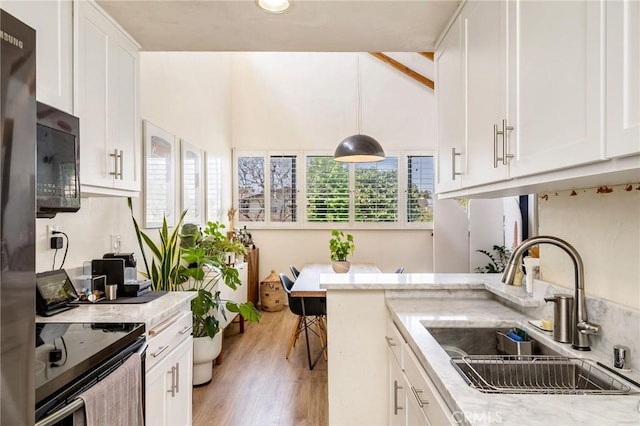 kitchen featuring a sink, white cabinetry, plenty of natural light, and range with electric stovetop