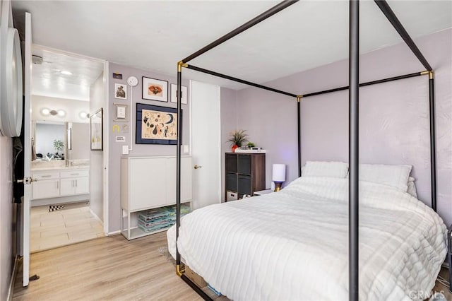 bedroom with ensuite bathroom and light wood-style floors