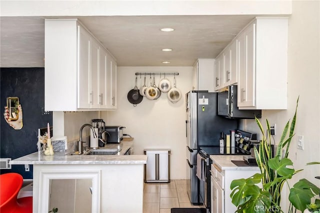 kitchen with a peninsula, light countertops, white cabinetry, stainless steel range with electric stovetop, and a sink
