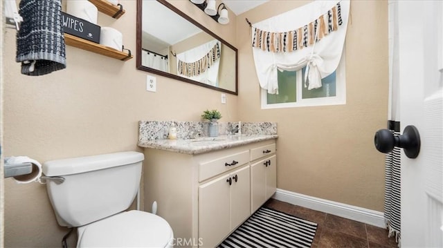 full bath featuring toilet, vanity, and baseboards