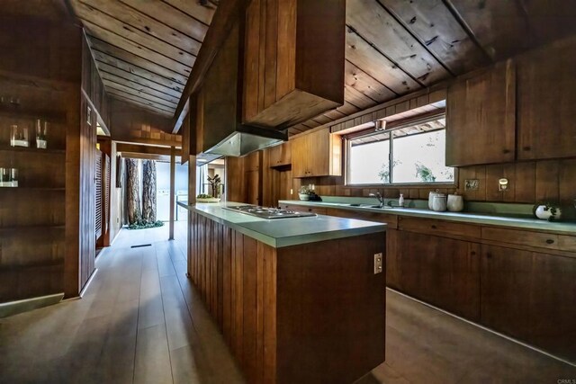 kitchen with wood ceiling, wood finished floors, stainless steel gas stovetop, and a kitchen island