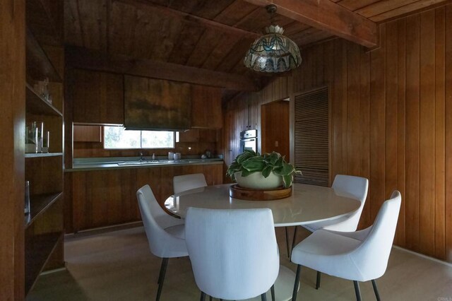 dining space featuring beamed ceiling, wood walls, and wooden ceiling