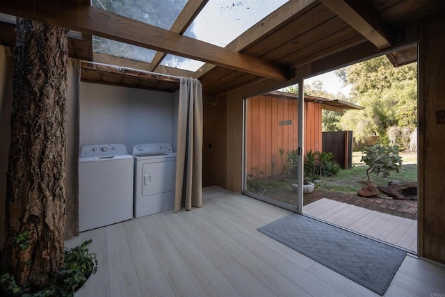 laundry area featuring washing machine and dryer, wood finished floors, laundry area, and a skylight