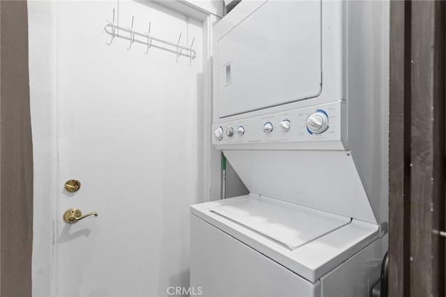 clothes washing area featuring stacked washer and clothes dryer and laundry area