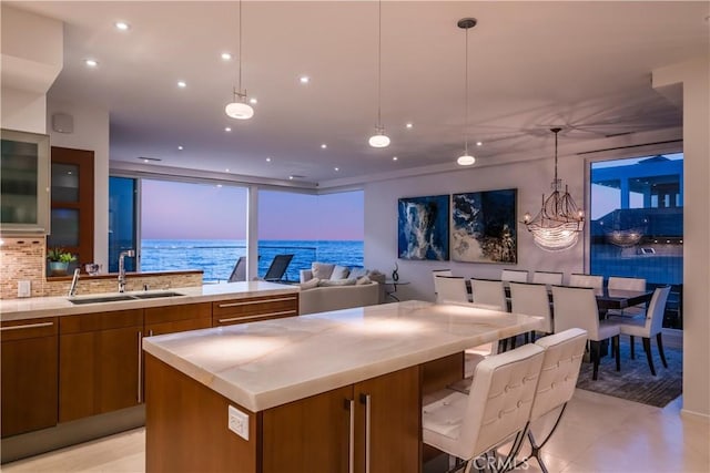 31091 Coast Hwy, Laguna Beach, CA 92651 - kitchen with decorative light fixtures, brown cabinetry, decorative backsplash, a water view, and a sink