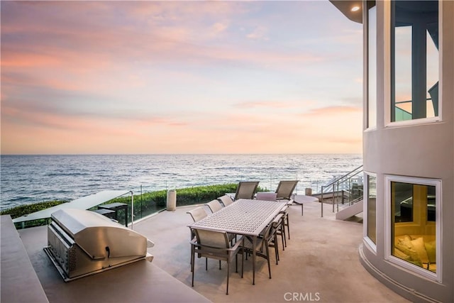 31091 Coast Hwy, Laguna Beach, CA 92651 - patio terrace at dusk featuring a view of the beach, an outdoor kitchen, a grill, a water view, and outdoor dining space