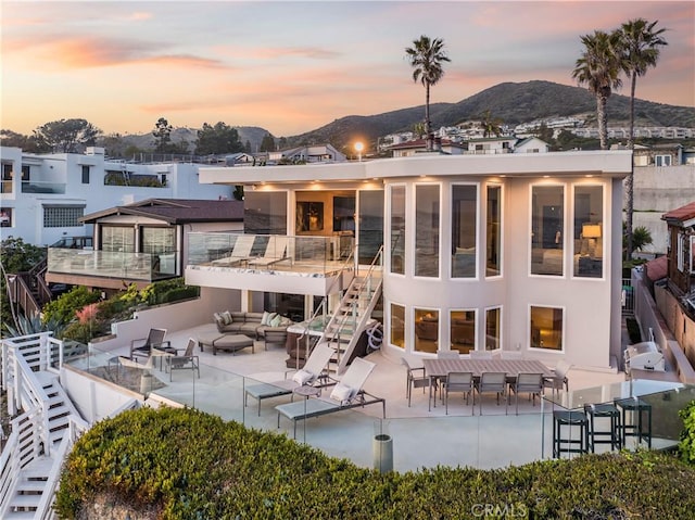 31091 Coast Hwy, Laguna Beach, CA 92651 - back of property at dusk with outdoor lounge area, stucco siding, a patio, stairs, and a mountain view