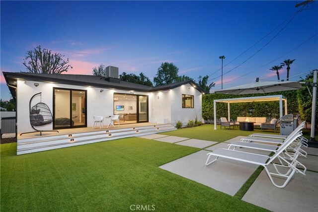 4739 Ventura Canyon Ave, Sherman Oaks, CA 91423 - back of house at dusk with outdoor lounge area, stucco siding, a yard, and a patio area