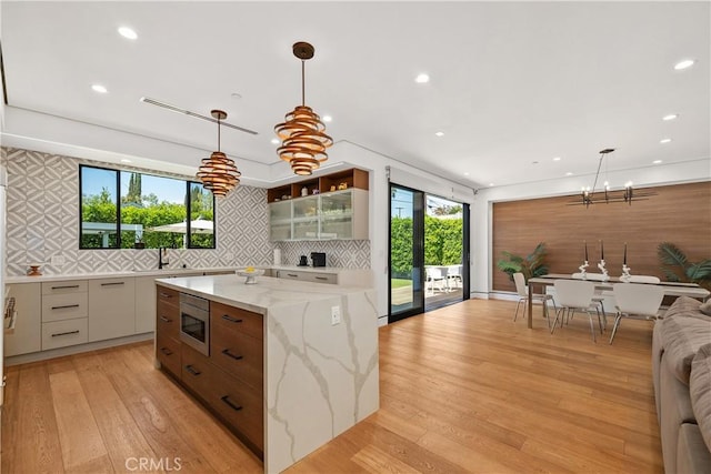 4739 Ventura Canyon Ave, Sherman Oaks, CA 91423 - kitchen with stainless steel microwave, glass insert cabinets, a sink, a chandelier, and backsplash