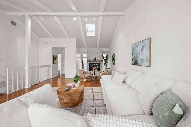 living room with visible vents, a brick fireplace, wood finished floors, high vaulted ceiling, and rail lighting