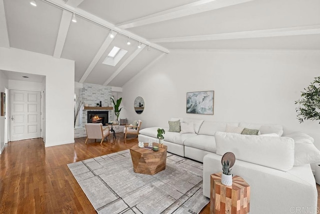 living room with lofted ceiling with skylight, baseboards, wood finished floors, a fireplace, and rail lighting