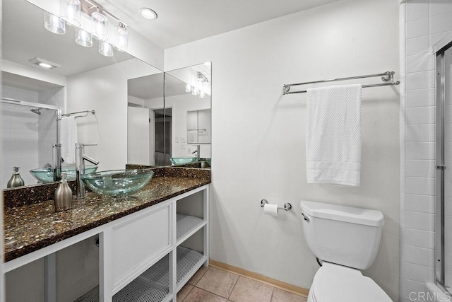 bathroom with a tile shower, tile patterned floors, toilet, vanity, and baseboards