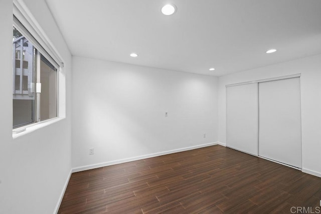 unfurnished bedroom featuring baseboards, wood finished floors, and recessed lighting