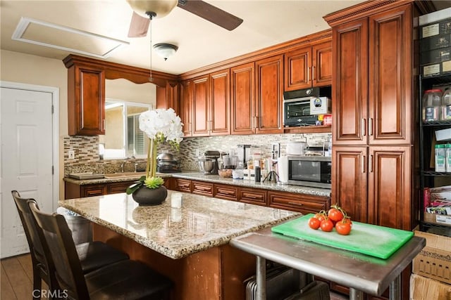 5717 4th Ave, Los Angeles, CA 90043 - kitchen featuring a sink, stainless steel microwave, light stone countertops, decorative backsplash, and a breakfast bar area