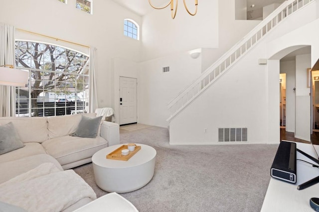 living area featuring arched walkways, carpet, visible vents, and stairway