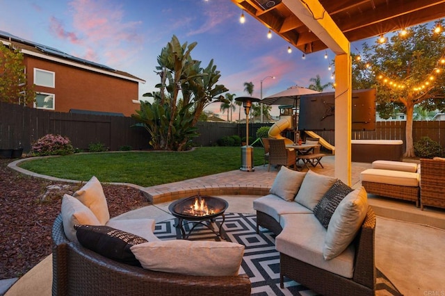 view of patio with a fenced backyard, an outdoor living space with a fire pit, and a playground