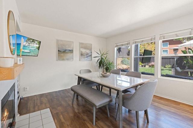 dining area with wood finished floors, baseboards, and a glass covered fireplace