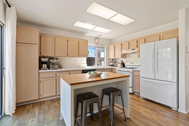 kitchen featuring butcher block countertops, white appliances, under cabinet range hood, light brown cabinetry, and wood finished floors