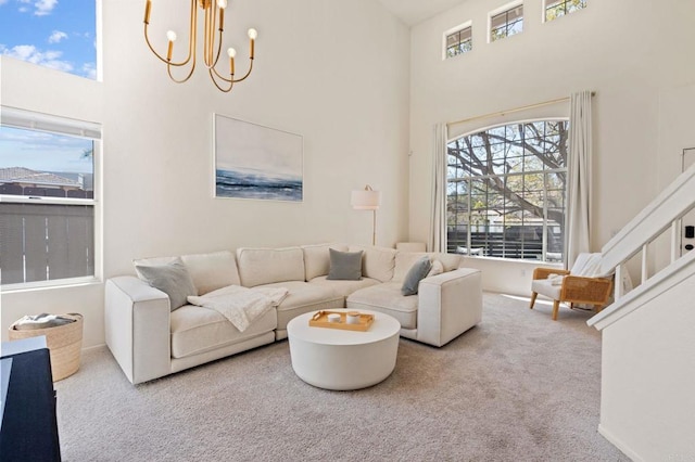 living room with carpet floors, a high ceiling, plenty of natural light, and a chandelier