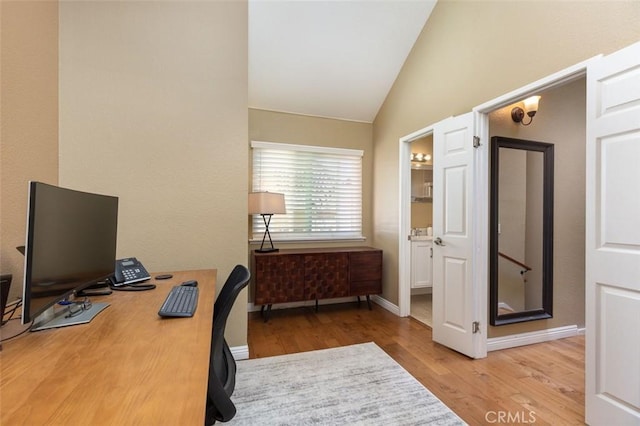 office featuring light wood finished floors, baseboards, and vaulted ceiling