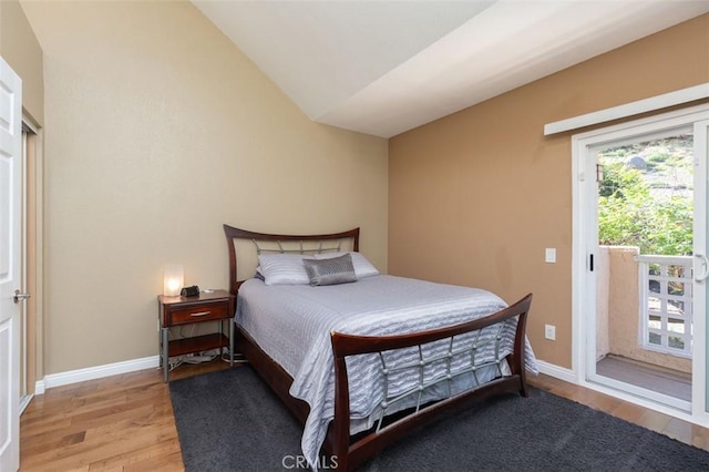 bedroom with access to exterior, light wood finished floors, vaulted ceiling, and baseboards