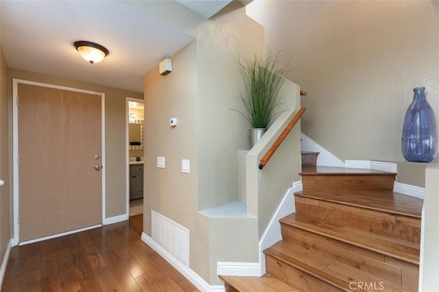 foyer entrance with hardwood / wood-style floors, baseboards, visible vents, and stairs