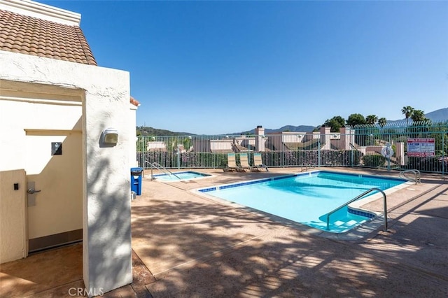 community pool with a patio area and fence