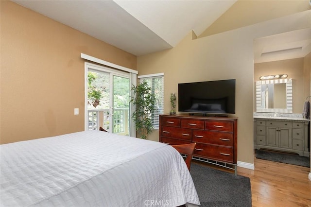 bedroom with light wood-style flooring, ensuite bathroom, baseboards, and vaulted ceiling