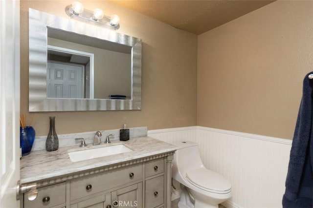 bathroom with toilet, wainscoting, and vanity