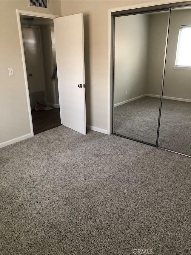 unfurnished bedroom with carpet, visible vents, a closet, and baseboards