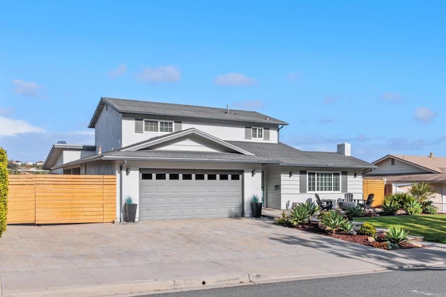 traditional-style house featuring stucco siding, a garage, fence, and decorative driveway