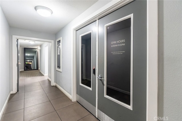 corridor with tile patterned flooring and baseboards
