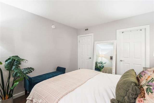 bedroom featuring visible vents, baseboards, and wood finished floors